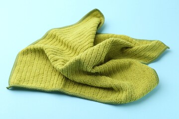 Clean green microfiber cloth on light blue background, closeup