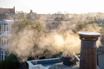 Smoke chimney pipe roof house sun autumn morning city Netherlands