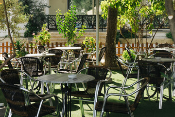 Outdoor beer garden with tables and chairs. Drinking coffee in the sun at a park café. Restaurant seating area in a natural, open-air setting. Relaxing at an outdoor café.