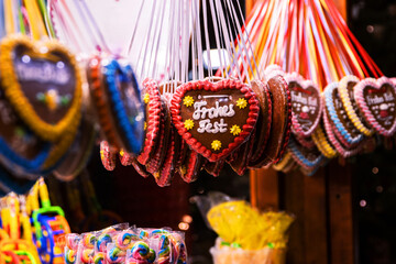 A colorful Christmas market stand in Berlin. Lady is selling heart shaped gingerbread with sweet messages, cotton candy, and vibrant sweets, highlighting the festive charm of German holiday tradition