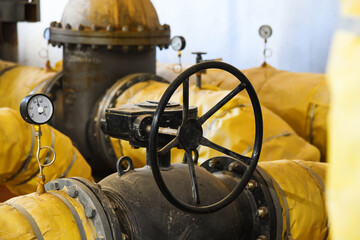 Pipes, shut-off valves and pumps of the heating system in an industrial boiler room