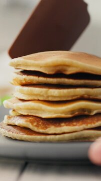 A stack of fluffy pancakes rests on a plate, golden-brown and delicious, suggesting a cozy breakfast experience in a homey kitchen atmosphere
