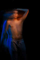 Naklejka premium blurred silhouette, young man posing in the dark with red and blue light in the studio