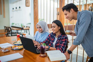 Group of indonesian students studying together using laptop in the coffee shop