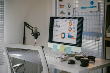 Modern home office with a computer showing business data, charts, and a professional microphone for podcasting or content creation