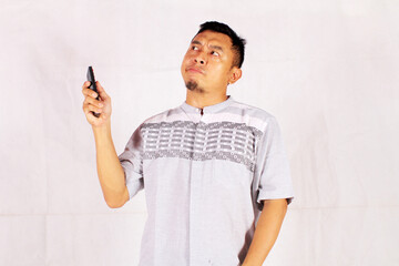 Asian man holding tv remote with surprised and confused expression
