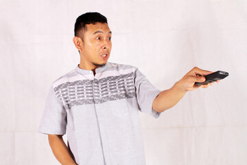 Asian man holding tv remote with surprised and confused expression
