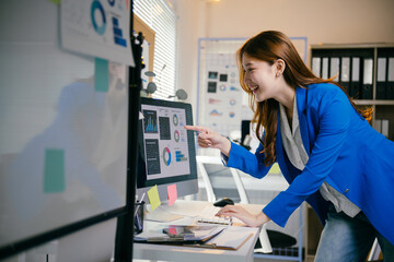 Smiling businesswoman reviews data on her computer in a modern office, focused and engaged,...