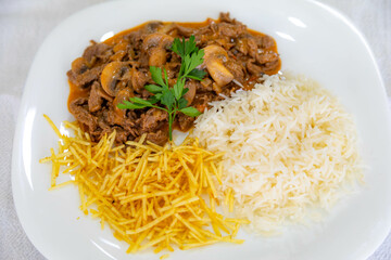 Traditional filet mignon stroganoff with mushrooms, French fries and rice