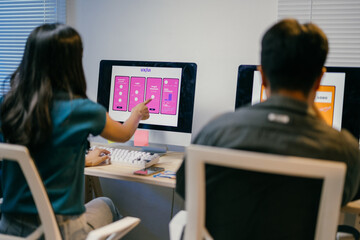 Two web designers are working in the office, analyzing the user interface of a mobile phone...