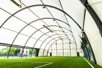 interior of a covered football pitch with grass and a football goal in the middle, light and space, grass roof, football stadium,