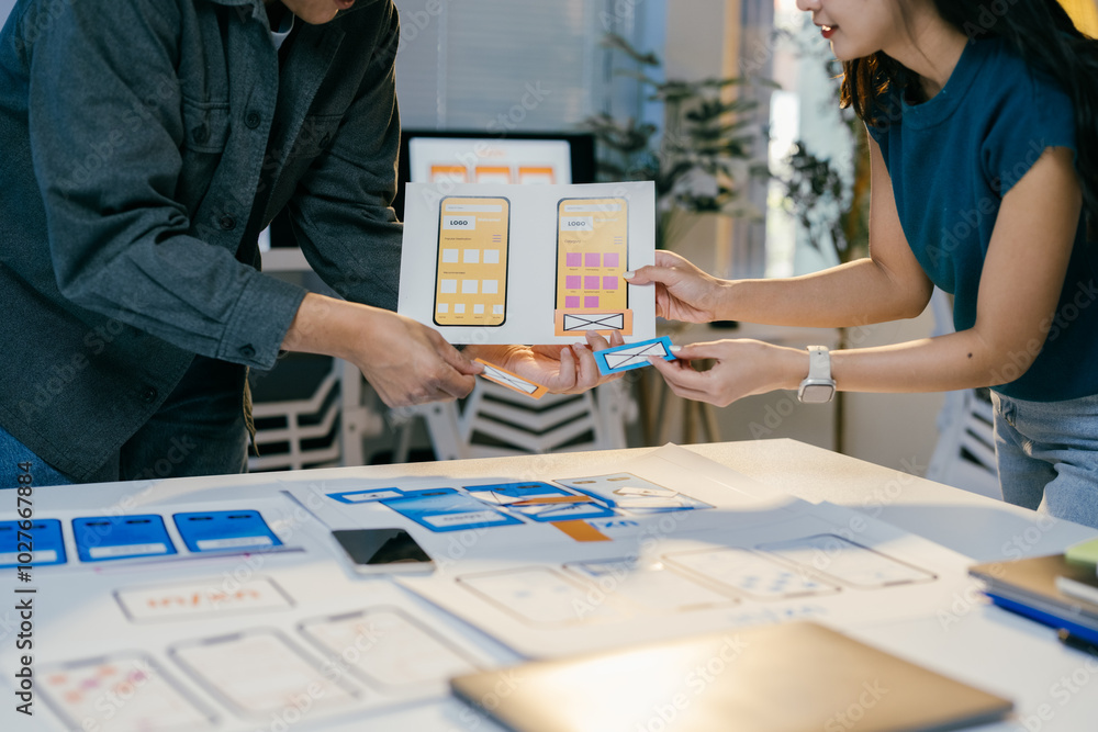 Poster Two ui/ux designers collaborating on new mobile app, selecting design elements, brainstorming in office, analyzing layouts for intuitive interface