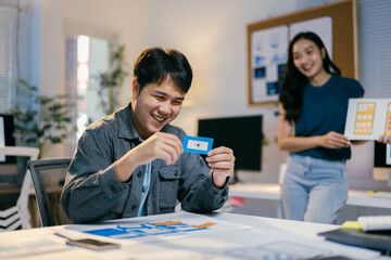 Two asian ui/ux designers happily collaborating on a new mobile app for their startup, working late into the night, immersed in a creative discussion to bring their vision to life