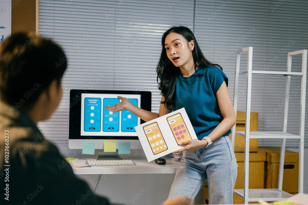 Poster young asian web designer is standing and presenting a mobile application interface design to her col