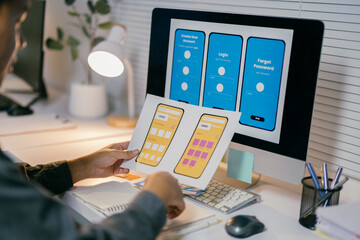 Ux designer is reviewing paper prototypes of a mobile app, comparing them to the design displayed...