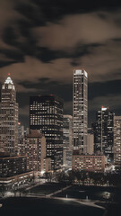 Fototapeta premium Night cityscape with glowing windows and dark clouds, urban architecture, modern design, city lights, night time, urban lifestyle. 