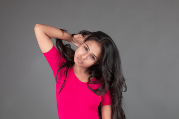Healthy young woman in red t-shirt and black leggings doing yoga and stretching exercises with...