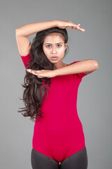 Healthy young woman in red t-shirt and black leggings doing yoga and stretching exercises with...