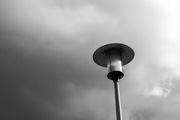 A tall lamp on a cloudy day in the park.