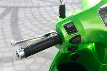 Motorbike throttle of a green scooter on a cobblestone street. Urban transport concept. City riding...