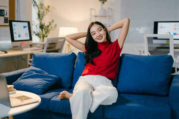 Obraz premium Young asian woman is relaxing on the couch in her home office after a long day of work, enjoying the comfort of her living room