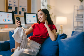 Asian businesswoman sits comfortably in her modern home office, smiling during a work video call on...
