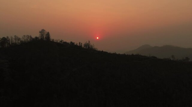 Beautiful Sunset, silhouetted against the warm hues of a setting sun in the hilly region and mountains in the background, Nepal