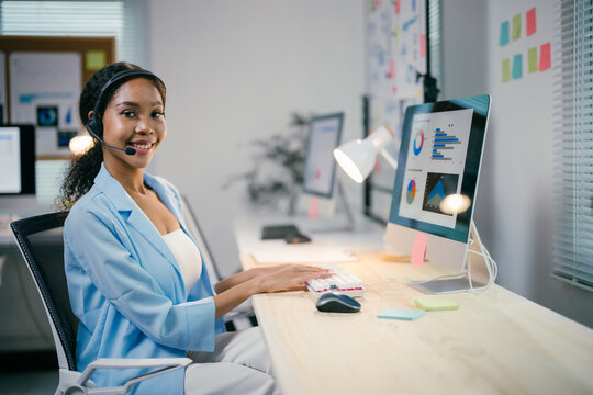 Confident african american businesswoman working joyfully at sleek desk in bustling office, fully engaged with computer, showcasing professionalism and expertise in corporate world