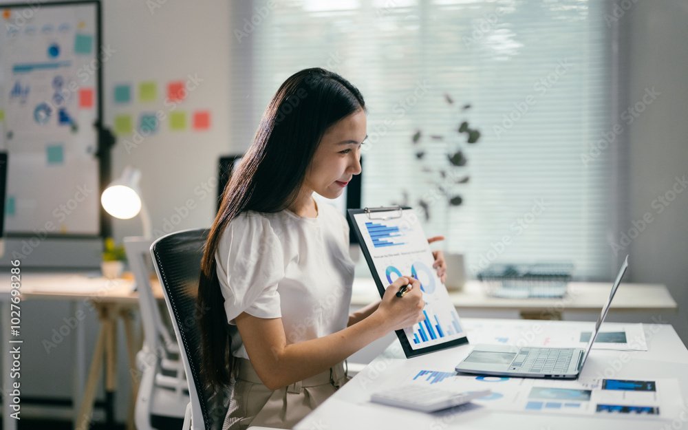 Poster young professional woman working on business project, reviewing data and analyzing graphs on a clipb