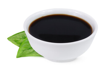Soy sauce in bowl and basil leaves on isolated white background.