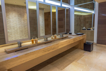 Modern restroom with marble countertops, large mirrors, soap dispensers and sleek sink fixtures. Mexico.