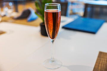 Close-up view of glass of sparkling wine on restaurant table with blurred background.