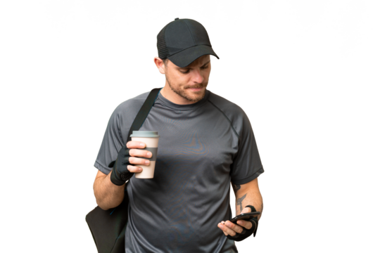 Young sport man with sport bag over isolated chroma key background holding coffee to take away and a mobile