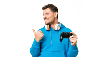 Brazilian man playing with a video game controller over isolated chroma key background pointing to the side to present a product
