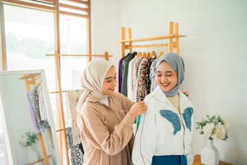Asian woman Muslim fashion designer measuring with a tape ruler the model's body in the workshop