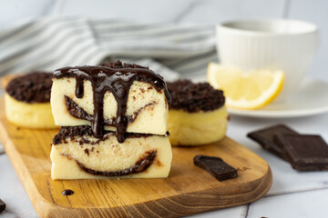 Stacked cheesecake slices with chocolate swirl filling and dripping chocolate ganache on wooden board. Concept of indulgent dessert, gourmet treat, and homemade baked goods for chocolate lovers