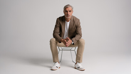 Happy middle aged business man sitting in chair isolated on white background. Happy mature...