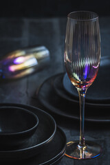 Pink shimmering champagne glass and black stoneware on a rustic black table, vertical
