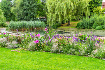Park in summer with a small pond and beautiful flower beds