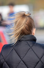 A woman with a ponytail is wearing a black jacket