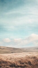 Fototapeta premium A serene landscape featuring gentle hills and a vast blue sky, perfect for evoking tranquility and natural beauty.