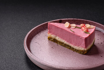 Piece of sweet cheesecake with pink cream cheese of raspberry or strawberry flavor