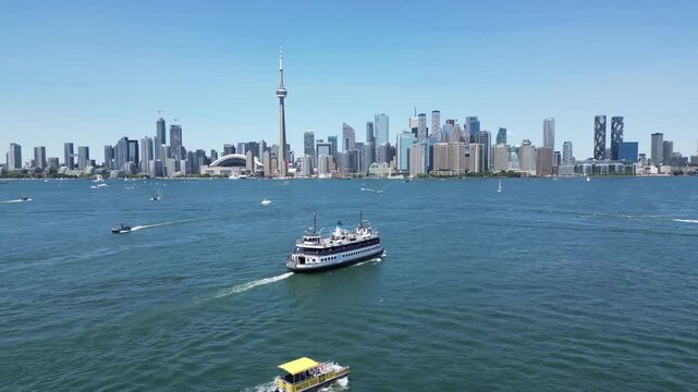 Ferry and water taxi sailing toward downtown Toronto skyline waterfront view from Centre Island showing the entire city shoreline including the famous CN tower