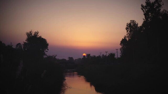 Beautiful Sunset, silhouetted against the warm hues of a setting sun and shadow in the river