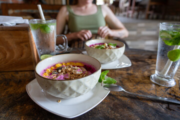 Bali Breakfast - 2 smoothie bowls with dragon fruit, pineapple, granola and mint, with Lime Mint Mojito Soda drink in local Indonesian Warung.