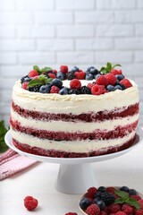 Tasty sponge cake with different berries and mint on white table
