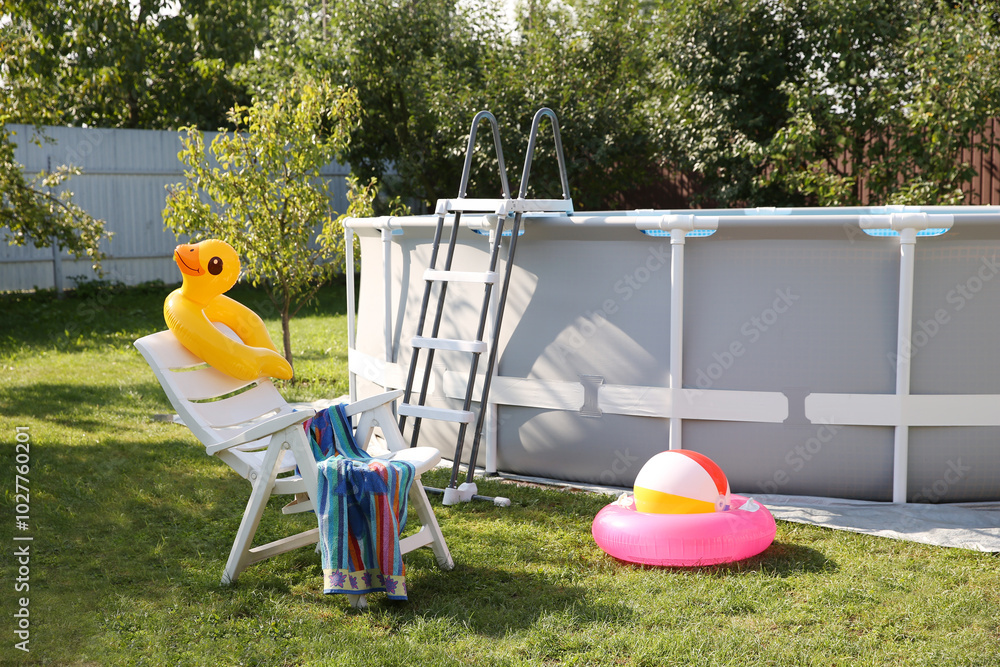 Sticker Above ground swimming pool, folding chair, towel, inflatable rings and ball in backyard