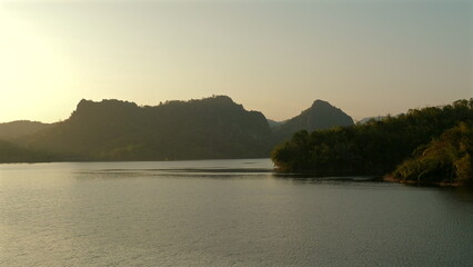 Serene lake at sunset with mountains and forested areas in background, providing tranquil and picturesque natural landscape. Scenic Beauty and Tranquility