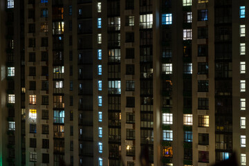 Night big city light residential building. The windows of the house glow in the dark. Modern...