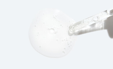 Transparent serum dripping from a dropper on white background capturing a minimalist aesthetic in skincare and beauty product photography